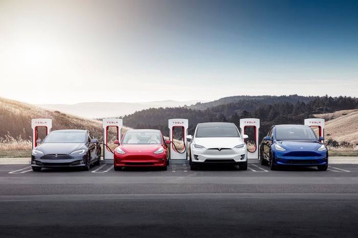 A Tesla Model S, Model 3, Model X, and Model Y plugged in at a supercharger station.