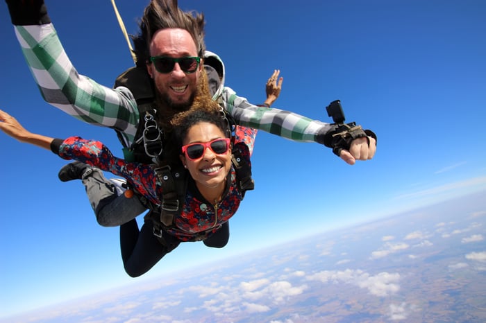 Two people looking at the camera and smiling during a tandem skydive. 