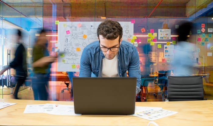 Close-up of person in office looking at laptop.