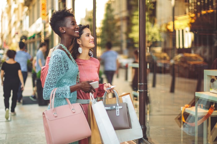 Two people shop and smile at products through the window.