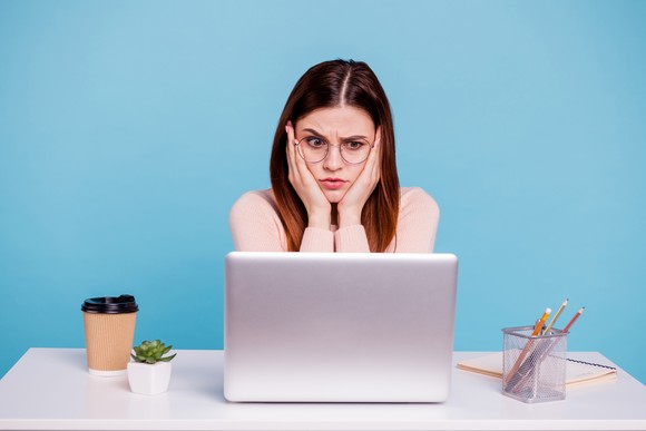 A bewildered person looks at a laptop screen.