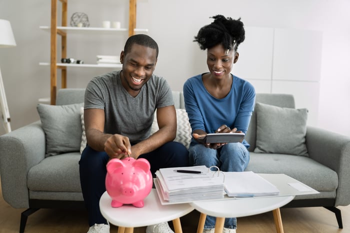 A couple putting money into a piggy bank.