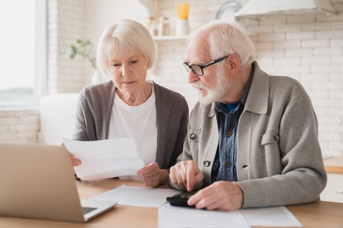 Two people at a laptop looking at documents.