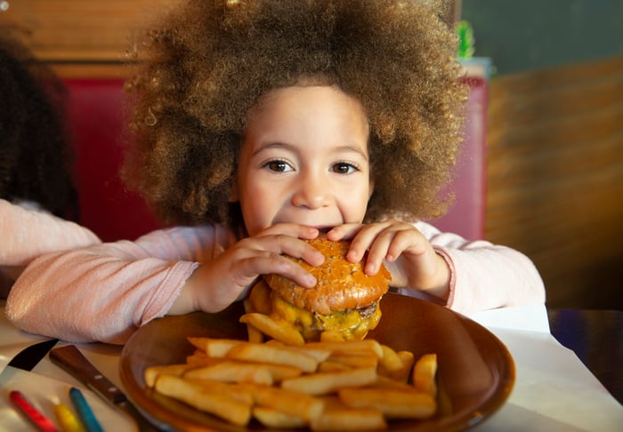 A child eating a hamburger and fries.