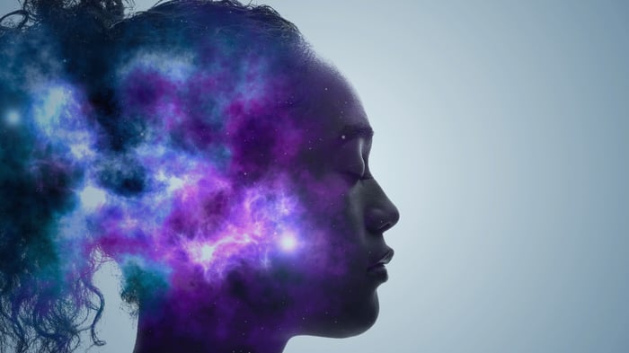 A side profile of a person's head, which has blue and purple atmospheric imagery projected onto it.