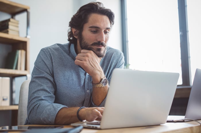 A person sits in an office using a laptop.