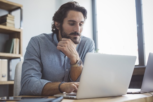 A person sits in an office using a laptop.
