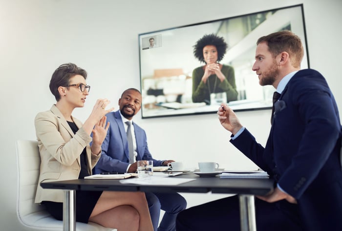 Three employees holding a videoconference with another person via Zoom Rooms.