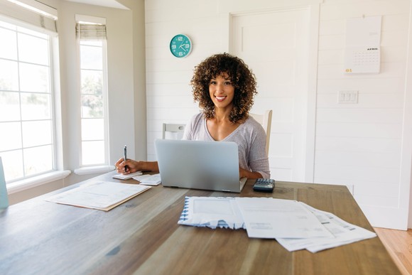A person sitting at a table with a notebook and computer.