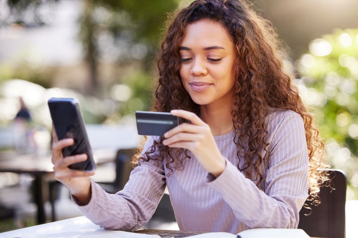 A person entering a credit card number into a smartphone.