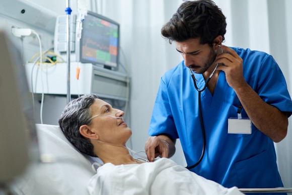 A person checking a patient using a stethoscope.