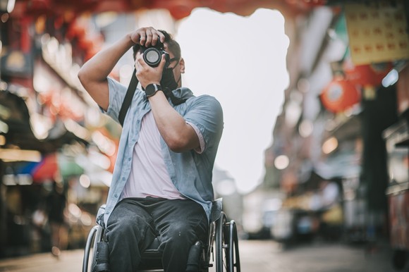 Man in wheelchair taking photograph.