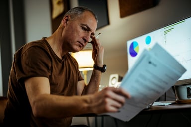 Middle aged man serious looking at documents GettyImages-1372745764