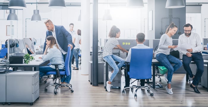 An office with six people in it, working together in pairs.