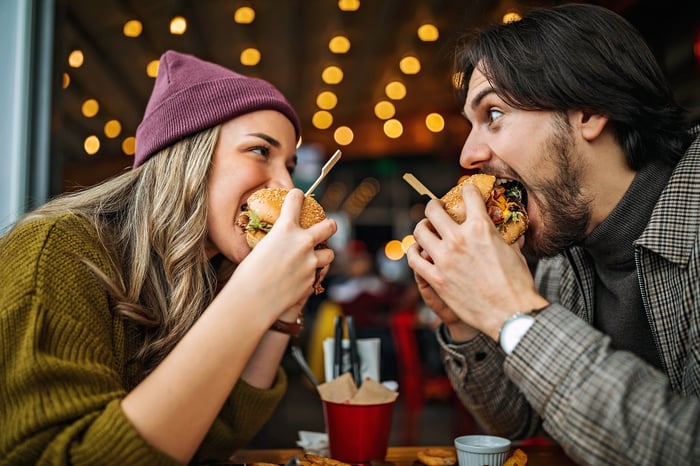 Two people eating hamburgers together.