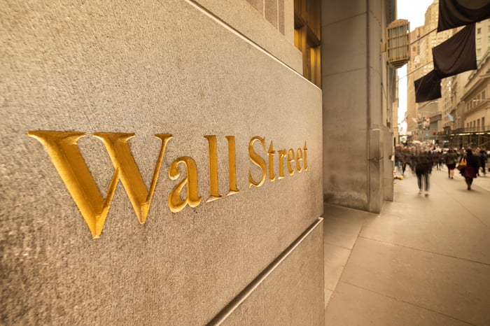 The words Wall Street, etched in gold color on the side of a building. 