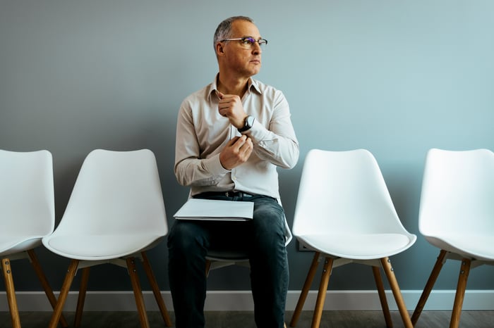 A person sits in an empty waiting room clutching a shirt.