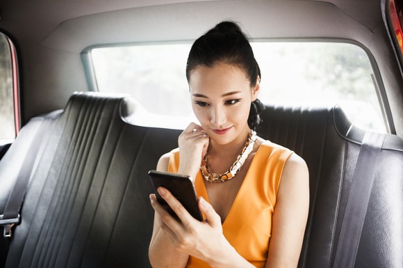 Woman in car looking at phone.