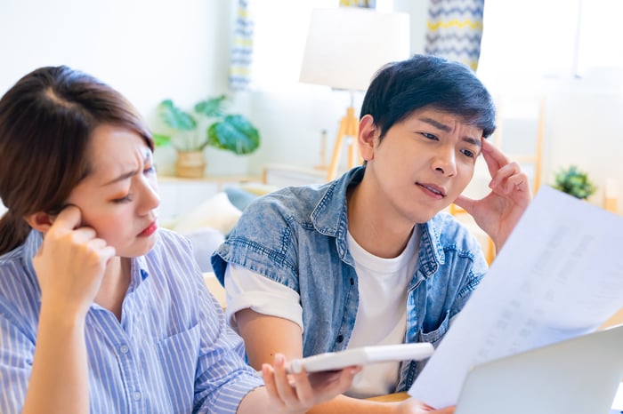 Two people looking at paperwork with a calculator.