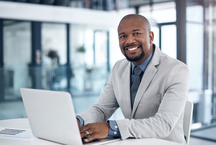 A smiling person at a laptop.