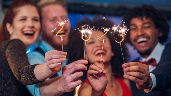 Smiling people holding sparklers showing 2023.