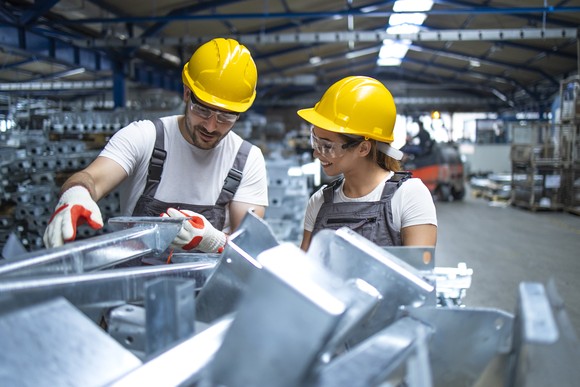 People in yellow hardhats looking at factory equipment.
