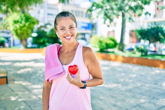 Someone with a towel over one shoulder holding a heart in their opposite hand.
