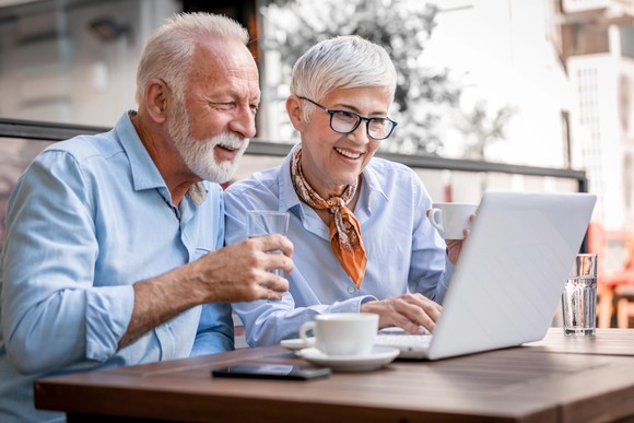 Two people sitting at a desk and looking at a computer.
