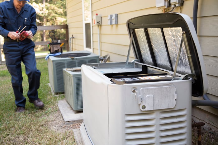 A technician services a backup home generator unit. 