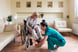 Sick Old Woman in a Wheelchair is Receiving a Help From a Young Nurse in Home Visit