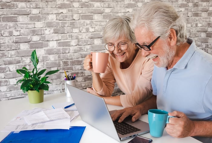 Two smiling people at a laptop.