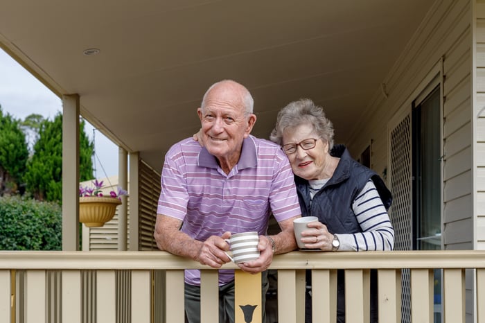 Two people on a deck holding coffee mugs.