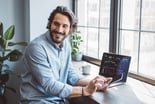 Person looking back from a stock chart on a laptop and smiling.