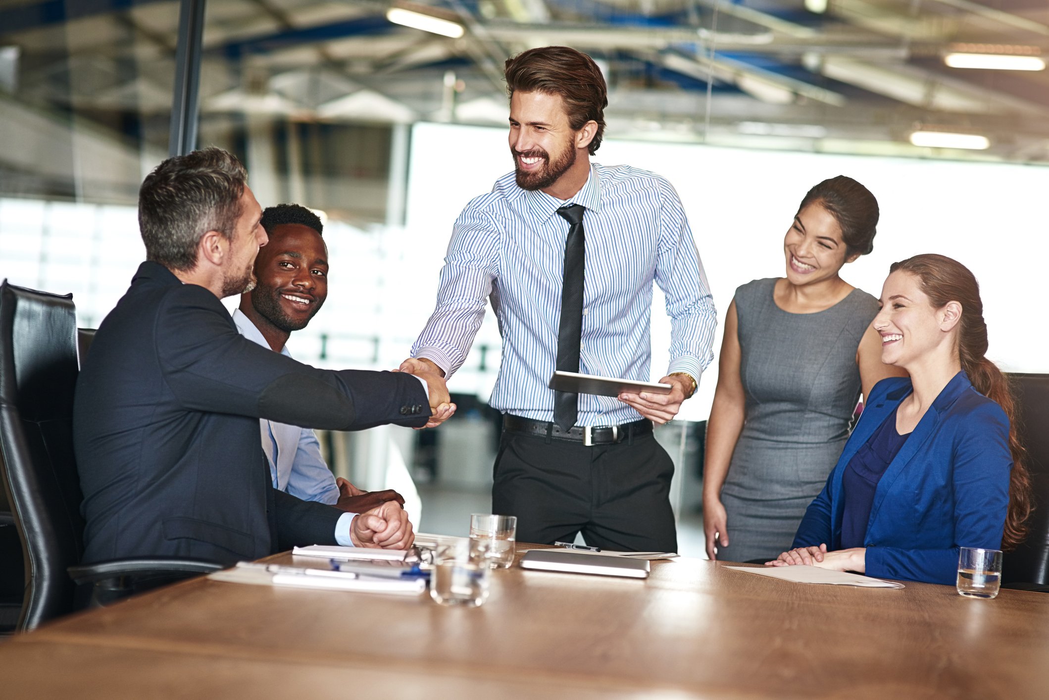 colleagues shake hands while in a meeting in a boardroom getty 2022