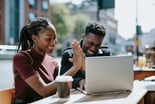 Couple high five in front of laptop.