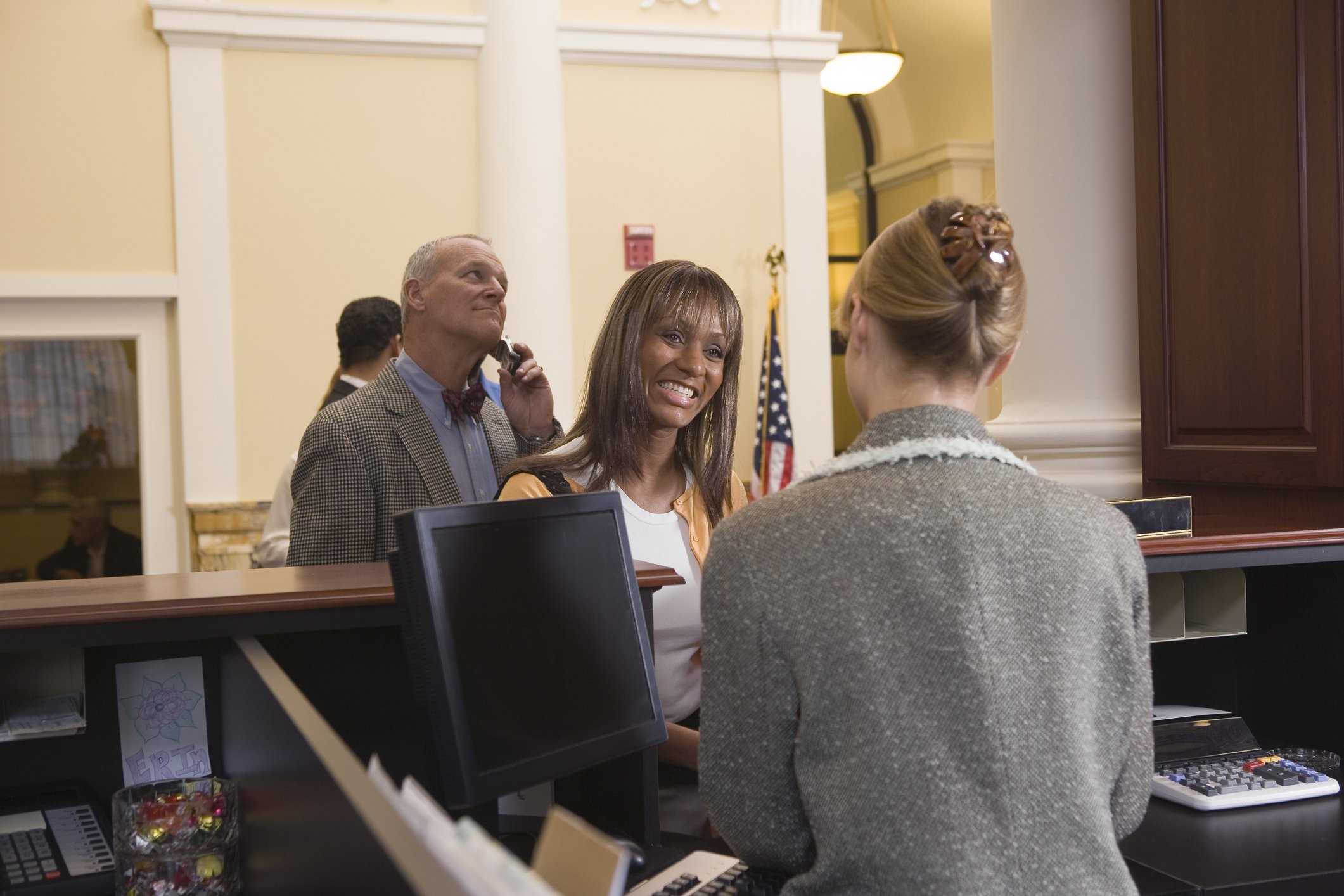 22_04_25 A bank teller providing service to a customer with a line behind them _GettyImages-86803709