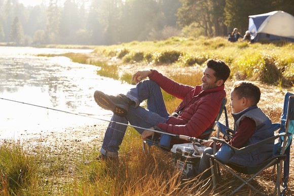 Two people fishing in the river while camping.