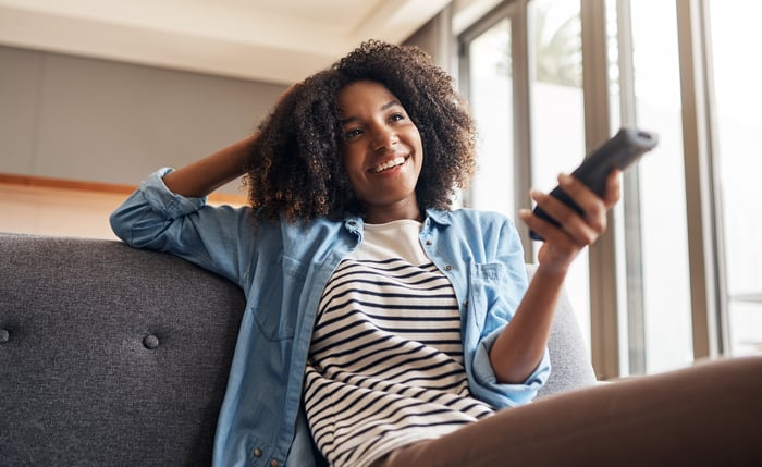 Someone smiling while channel surfing from a couch.