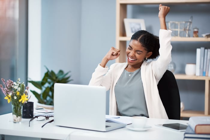 Happy person cheering in front of computer. 