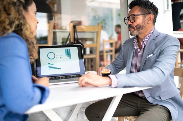 Financial advisor advises client before a laptop.