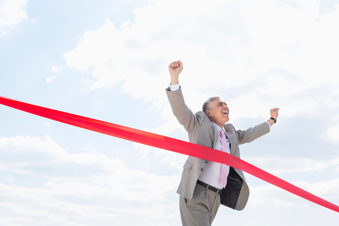 A person in a business suit crosses a finish line.
