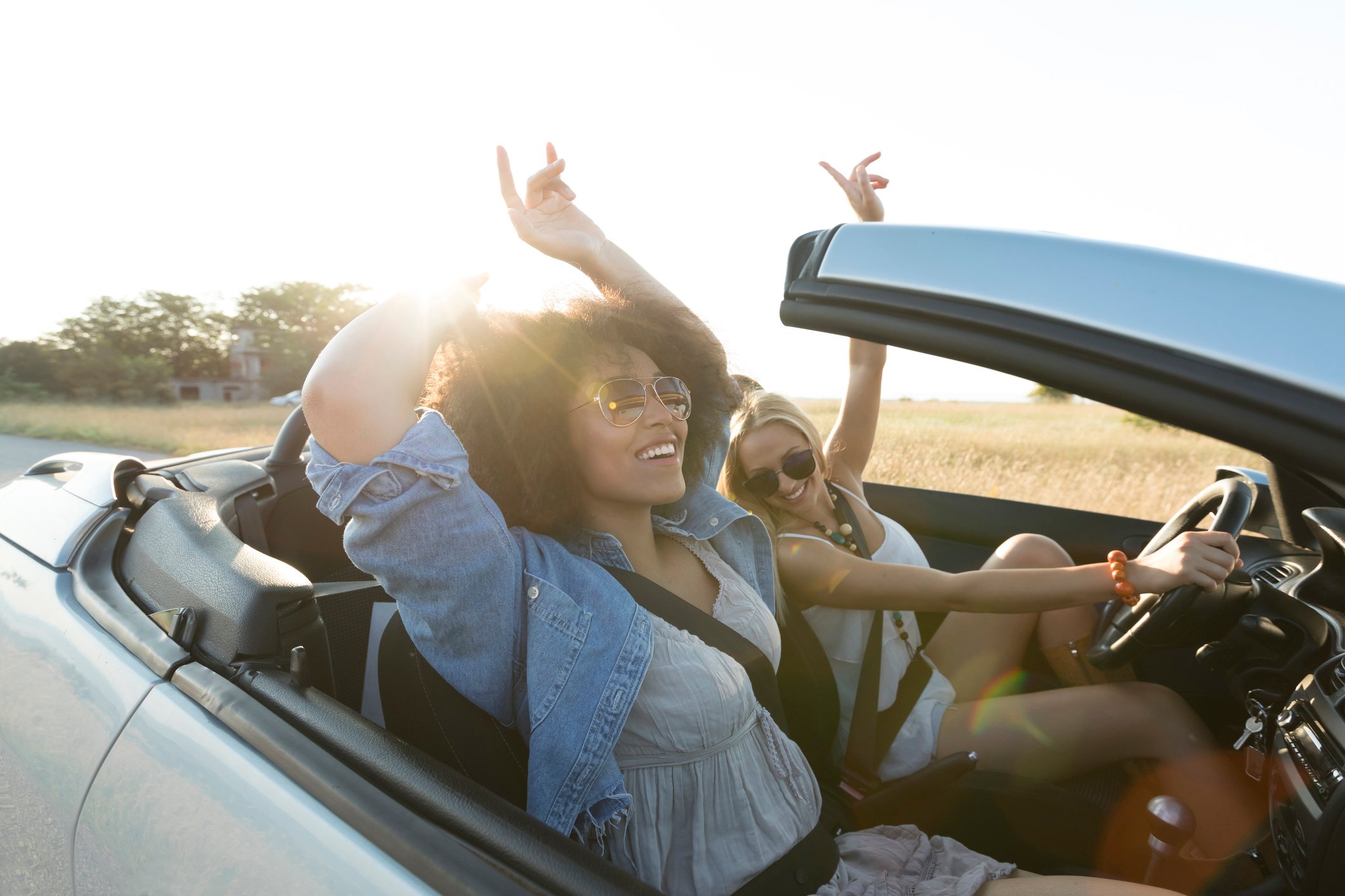 Two people enjoying a daylight ride in a convertible car