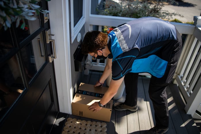 Amazon delivery person placing a package in front of a door.