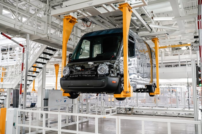 Rivian utility van sitting on a hoist during the manufacturing process.