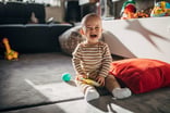 Upset baby sitting on the floor and crying