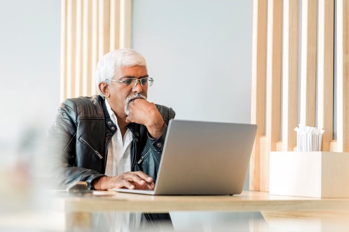 Person with a serious expression looking at a laptop.