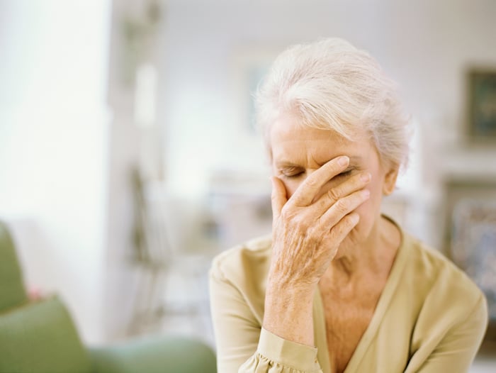 Stressed person with their hand over their face.