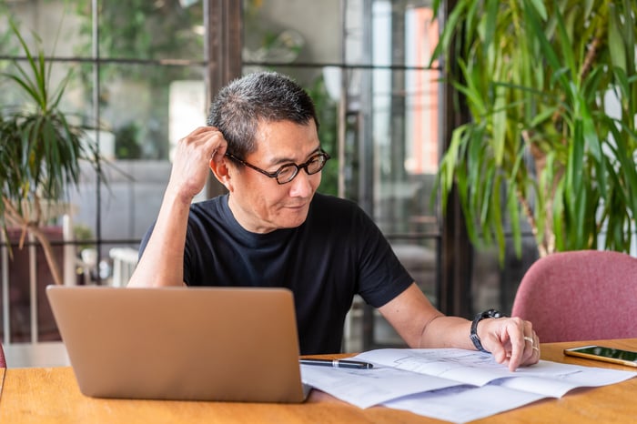 Person sitting in front of laptop studying documents.