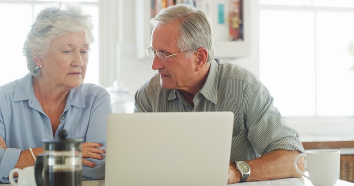 Two people at a laptop with serious expressions.