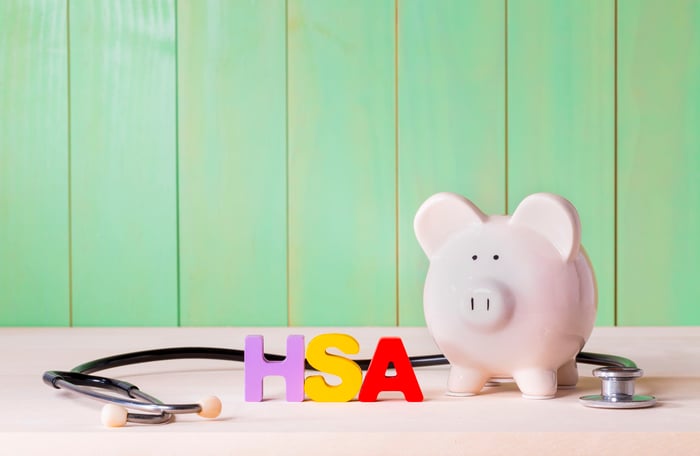 A piggy bank on a table with a stethoscope and blocks spelling HSA.